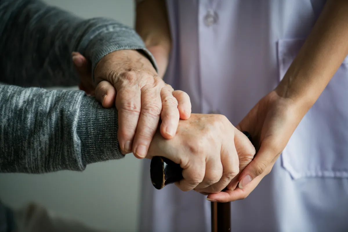 Hände einer Pflegekraft und eines Seniors