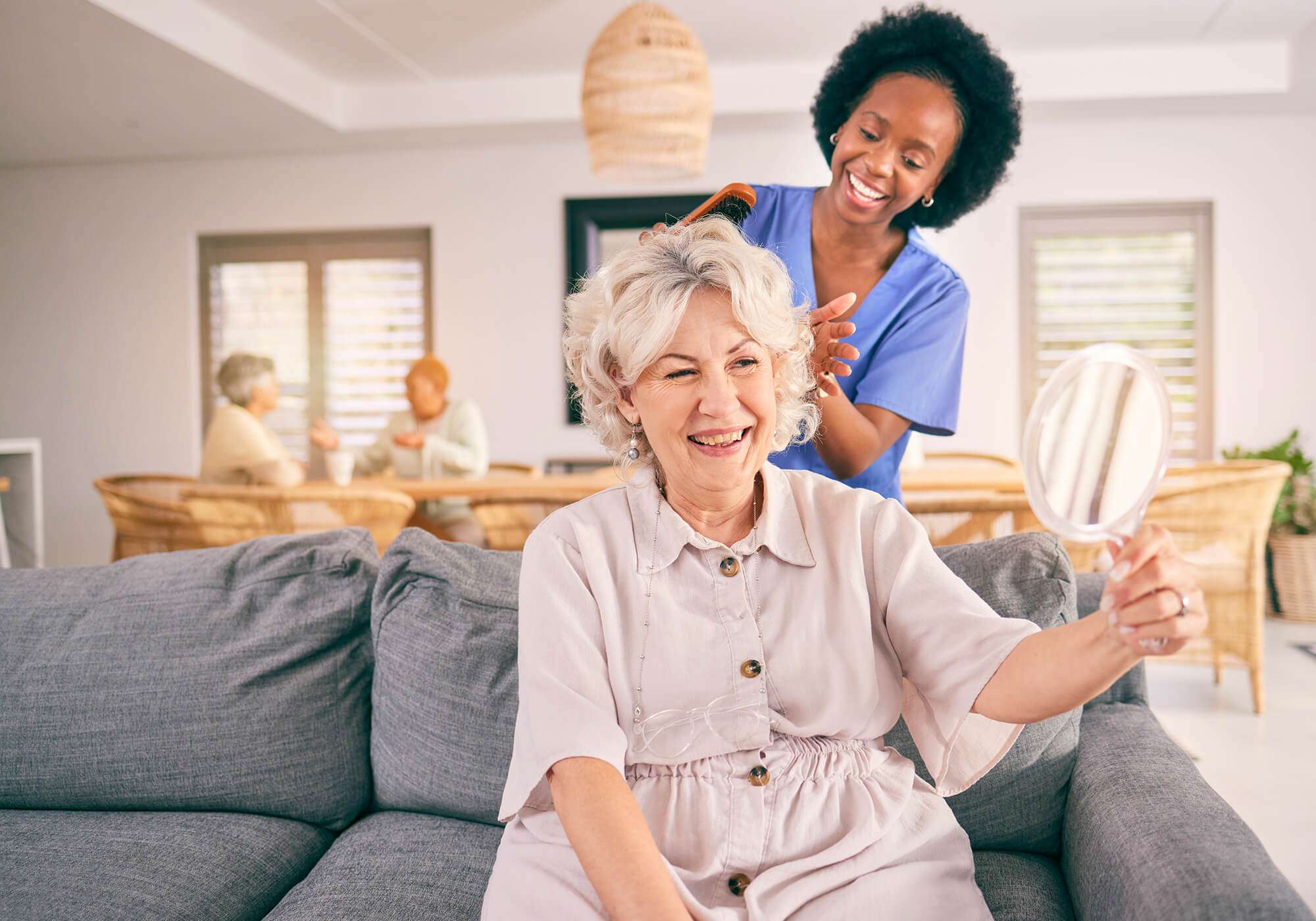 Pflegekraft kämmt einer Seniorin die Haare